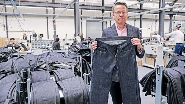 Besuch in der FIT: Leiter Uwe Gansfort zeigt eine frisch gefertigte Jeans.