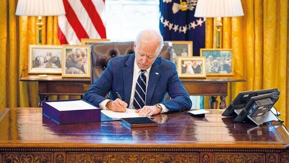 Vor Flaggen und Familienfotos: US-Präsident Joe Biden unterzeichnet das Gesetz zum Konjunkturprogramm.