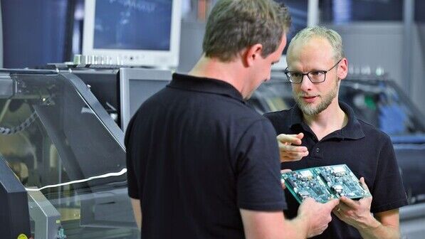 Fachlicher Austausch: Arne Dethlefs begutachtet mit einem Kollegen eine Leiterplatte. Foto: Augustin