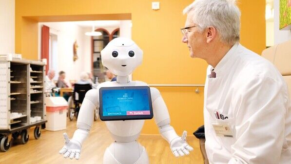 Diese Augen: Hilfsroboter Pepper mit seinem „Chef“, Professor Ralf-Joachim Schulz, auf dem Flur des Kölner Krankenhauses.