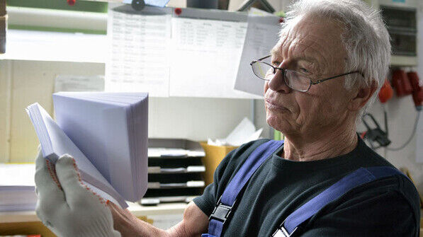Geschultes Auge;: Pensionär Wilhelm Zangler bei einer Sichtkontrolle von Kuverts. Er arbeitet noch stundenweise im Betrieb. Foto: Scheffler