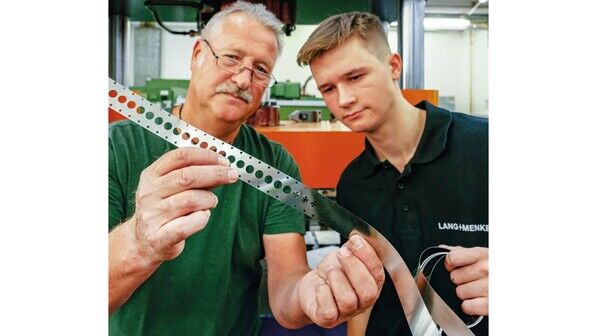 Ausgestanzt: Ausbildungsleiter Ulrich Hertel kontrolliert mit David Zuzanski an einem Stanzstreifen, ob das Werkzeug richtig arbeitet.