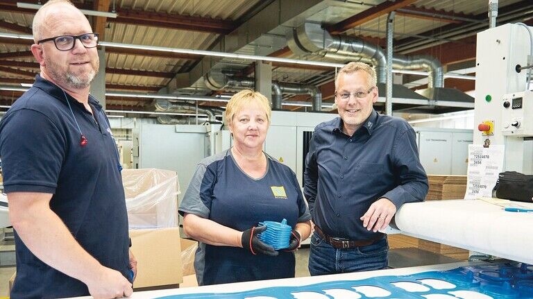 Ein Chef zum Anfassen: Uwe Belikan (rechts) im Gespräch mit Mitarbeiterin Marion Schade und Produktionsleiter Eddi Döpping. Mit dieser Maschine werden Schutzkappen produziert.