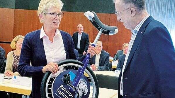 Symbolisches Geschenk: Angelique Renkhoff-Mücke (vbm) überreicht Johann Horn ein Einrad – zum „Balance-Halten“.