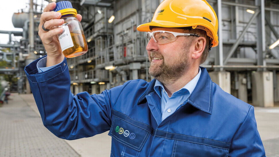 Pyrolyseöl aus Kunststoffabfällen: Ein Mitarbeiter der BASF mit einer Probe vor dem Steamcracker.